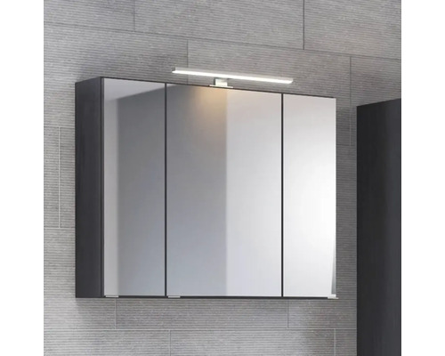 Dreitüriger Badezimmer-Spiegelschrank mit integrierter LED-Aufsatzleuchte und dunklem Korpus vor grauer Wand.