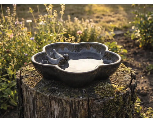 Keramik Vogeltränke mit zwei Vogel Figuren auf einem Baumstumpf im Garten.
