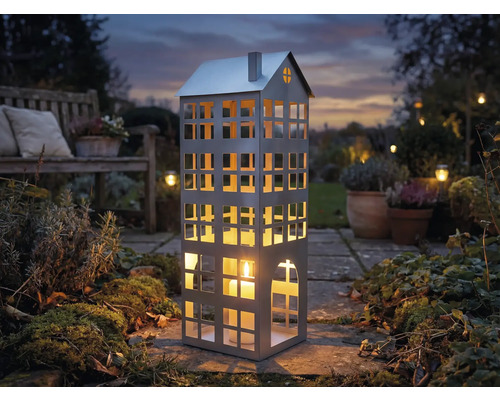 Dekorative Laterne in Hausform mit Kerze im Garten.