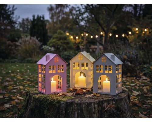 Drei Hauslaternen mit Kerzen auf einem Baumstumpf im Garten