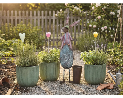Gartenszene mit bepflanzten Töpfen, Metallhase und Dekorationen auf einem Kiesweg