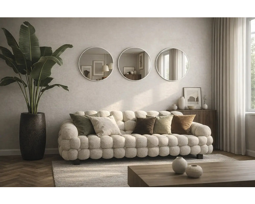 Wohnzimmer mit Sofa, Kissen, runden Spiegeln und Zimmerpflanze