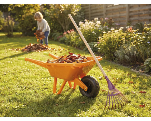 Garten Szene mit Schubkarre, Rechen und Kind beim Laubsammeln
