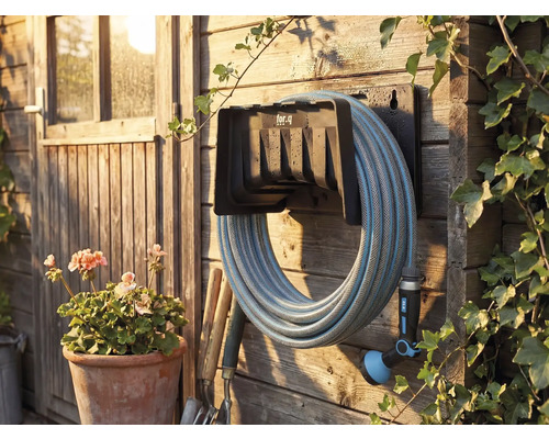 Gartenszene mit Schlauchaufroller, montiert an einer Holzwand mit Gartenschlauch