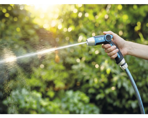 Eine Hand hält eine Gartenspritze von for_q, aus der ein Wasserstrahl kommt.