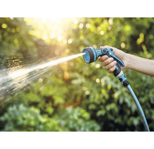 Eine Hand hält eine Gartenspritze, aus der Wasser spritzt