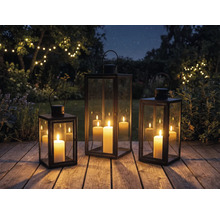 Drei Laternen mit Kerzen auf einer Holzterrasse im Garten