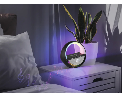 Nachttischszene mit mehrfarbiger Lampe, Lautsprecher und kabelloser Ladestation neben einer Zimmerpflanze