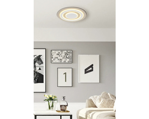 Moderne Wohnraumgestaltung mit runder Deckenleuchte und dekorativen Bildern an der Wand