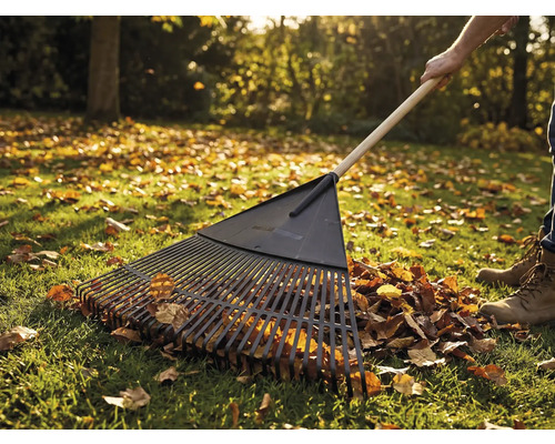 Laub-Rechen mit Holzstiel im Einsatz auf einer Rasenfläche mit Herbstlaub