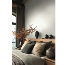 Schlafzimmer mit Holzbett, Kissen, Decken und Vasen
