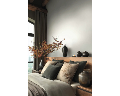 Schlafzimmer mit Holzbett, Kissen, Decken und Vasen