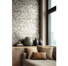 Vliestapete mit Kiefernbaummuster in einem Wohnzimmer mit Sofa, Zierkissen und Keramikvasen auf einem Sideboard neben einem Fenster.