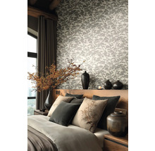 Modernes Schlafzimmer mit Vliestapete im Wald-Design, Holzbett mit grauen und beigen Kissen sowie dekorativen Vasen.