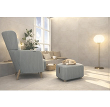 Wohnzimmer mit Sessel, Hocker, Stehlampe und einer Katze, die auf dem Hocker schläft