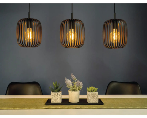 Szene mit drei Pendelleuchten über einem Tisch mit Dekoration und Stühlen.