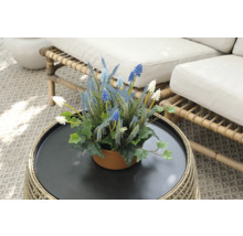 Dekorative Kunstblumen in einem Topf auf einem Rattantisch