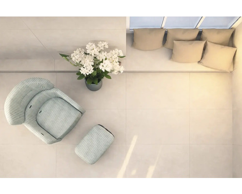 Helle Räumlichkeit mit Sessel, Fußhocker, Blumenarrangement und Couch mit Kissen, von oben aufgenommen