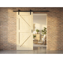 Holzschiebetür im Landhausstil mit Beschlägen vor einer Ziegelwand