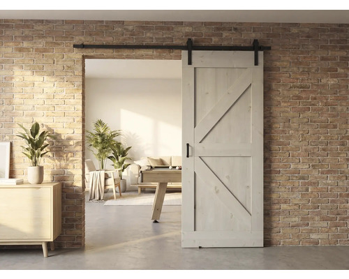 Holzschiebetür vor einer Ziegelwand mit Blick in ein helles Wohnzimmer