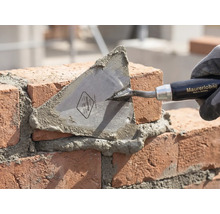 Maurerkelle beim Mauern von Ziegelsteinen mit Mörtel