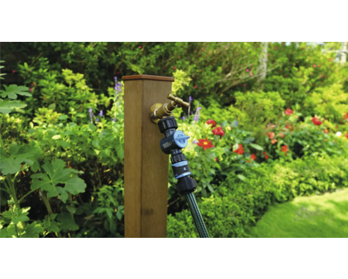 Gartenszene mit Wasserhahn, Verteiler und Schlauch an einem Holzpfosten