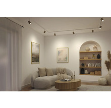 Modernes Wohnzimmer mit weißem Schienensystem an der Decke, hellem Sofa, Holz-Couchtisch und beleuchteter Wandnische mit Regalen.