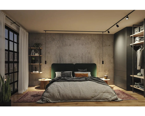 Modernes Schlafzimmer mit Wand in Betonoptik, Doppelbett mit grünem Kopfteil und schwarzem Schienensystem mit Strahlern und Pendelleuchten.