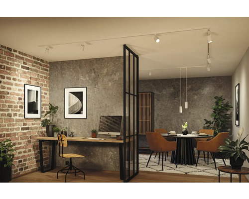Modernes Industrie-Interieur mit weißem Schienensystem an der Decke, das Arbeitsplatz und Essbereich vor Beton- und Ziegelwänden beleuchtet.