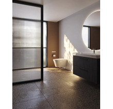 Modernes Badezimmer mit wandhängendem WC, dunklem Waschtischunterschrank, rundem beleuchtetem Spiegel und Glas-Trennwand.