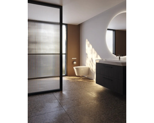 Modernes Badezimmer mit wandhängendem WC, dunklem Waschtischunterschrank, rundem beleuchtetem Spiegel und Glas-Trennwand.