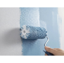 Eine Person streicht eine Wand mit einer Farbwalze.