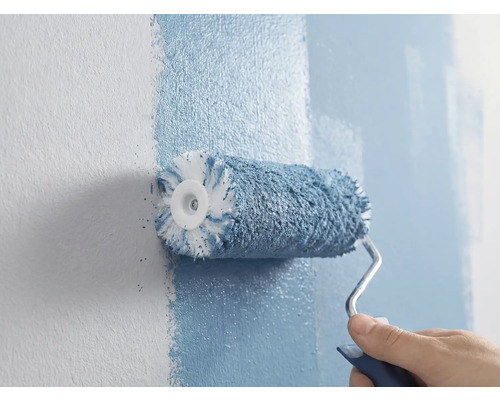 Eine Person streicht eine Wand mit einer Farbwalze.