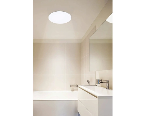 Helles Badezimmer mit Badewanne, Waschtisch und runder Deckenleuchte