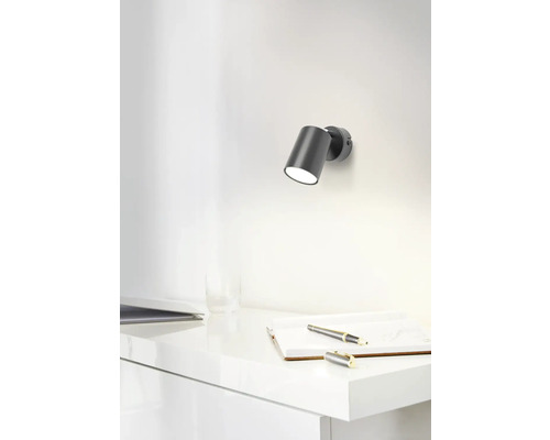 Szene mit einer Wandleuchte über einem Schreibtisch mit Notizbuch und Stift