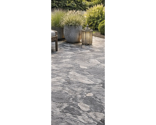 Verlegter Terrassenboden mit Pflanzgefäßen und Windlicht im Garten