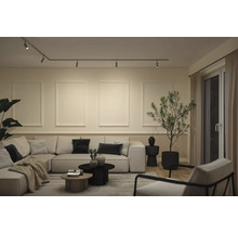Modernes helles Wohnzimmer mit großem Ecksofa, Deckenschienensystem, dekorativen Wandleisten im Rahmendesign und einer großen Zimmerpflanze.