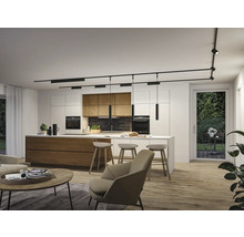 Moderne Küche und Wohnbereich mit schwarzem Schienensystem an der Decke, Strahlern und Pendelleuchten über einer Kochinsel aus Holz.