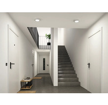 Moderner heller Flur mit dunkler Treppe, weißen Türen mit schwarzen Griffen und runden Decken-Einbauleuchten.