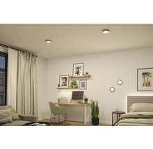 Modernes, helles Zimmer mit runden LED-Deckenstrahlern und Wandleuchten, eingerichtet mit Schreibtisch, Sofa, Bett und Zimmerpflanzen.