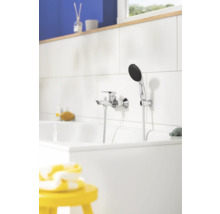 Moderne Badewannenarmatur in Chrom-Optik mit Handbrause an einer weiß gefliesten Wand in einem hellen Badezimmer.
