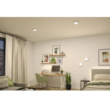 Moderner, hell gestalteter Wohnraum mit Schreibtisch und Bett, beleuchtet durch quadratische LED Einbauleuchten an der Decke und Wandleuchten.