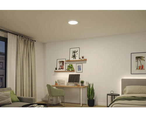 Runde LED-Deckenleuchte in einem hellen, modern eingerichteten Zimmer mit Schreibtisch, Wandregalen und Bett.