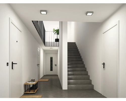 Moderner heller Flur mit weißen Innentüren, schwarzen Griffen, dunkelgrauer Treppe und quadratischen Deckenleuchten.
