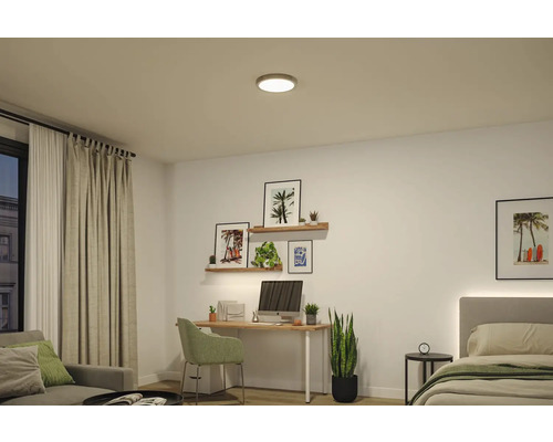 Runde LED Deckenleuchte in einem hellen, organisierten Zimmer mit Holzschreibtisch, Sofa, Bett und Zimmerpflanzen.