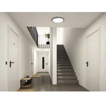 Moderner, heller Flur mit einer runden LED Deckenleuchte, weißen Türen und einer dunkelgrauen Treppe.