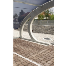 Moderner Carport mit bogenförmigem Stützpfeiler, blauem Dach, Pflastersteinen und weißer Kiesfläche.