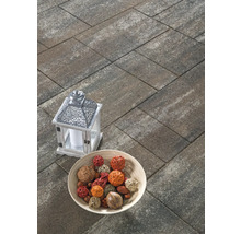 Rechteckige Pflastersteine aus Beton in schattierter Optik auf einer Terrasse, dekoriert mit einer Laterne und einer Schale.