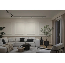 Modernes Wohnzimmer mit Schienensystem an der Decke, Wandleisten, großem Ecksofa, Couchtischen und einer Zimmerpflanze.