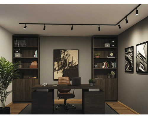 Modernes Heimbüro mit schwarzem L-förmigem Schienensystem und Strahlern an der Decke. Der Raum hat dunkle Holzregale, einen Schreibtisch und Wandbilder.